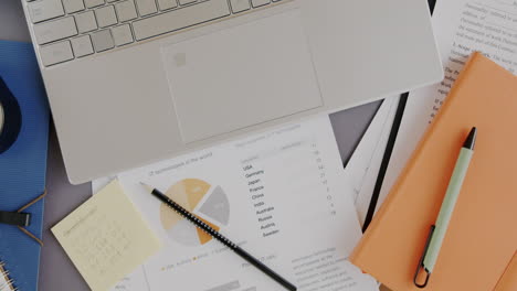 busy workspace with laptop, documents, and charts