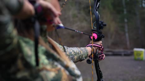 a girl holding a bow and arrow which is pulled back and ready to fire at the target