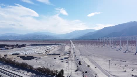 interminable carretera desértica y enorme granja de turbinas eólicas en tierras arenosas del desierto, vista aérea de drones