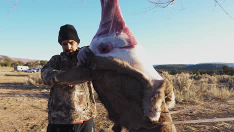 successful hunter skins the coat off his buck kill with a knife