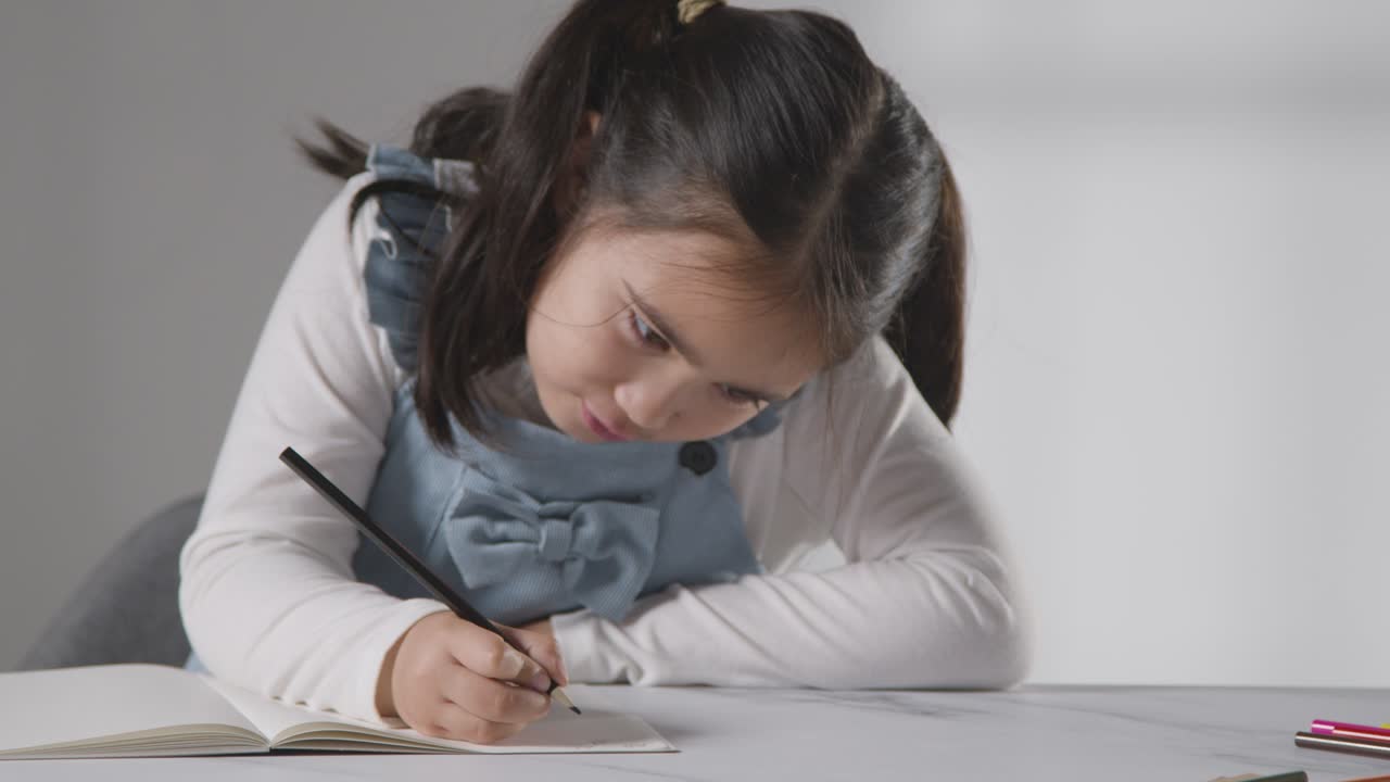 foto de estudio de una joven en la mesa escribiendo en el libro escolar 1