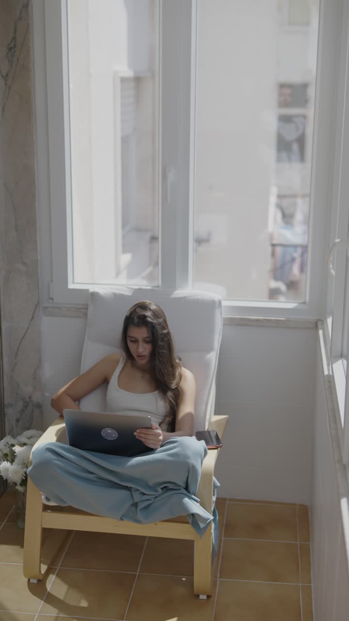 Donna che lavora al portatile sul balcone