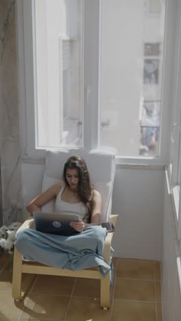 mujer trabajando en una computadora portátil en el balcón