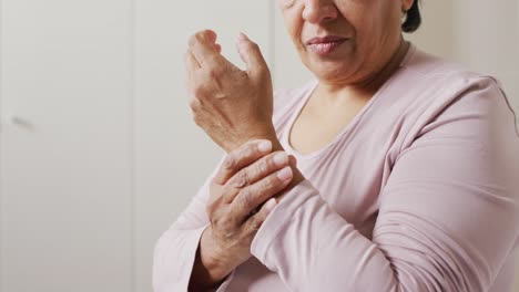 Close-up-of-african-american-senior-woman-holding-her-hand-in-pain-at-home