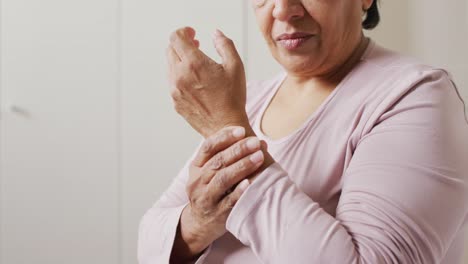 close up of african american senior woman holding her hand in pain at home