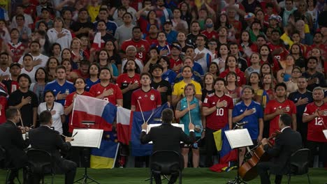 a vibrant display of unity: fans from different nations stand together, singing the anthem with passion and pride at a major international sporting event