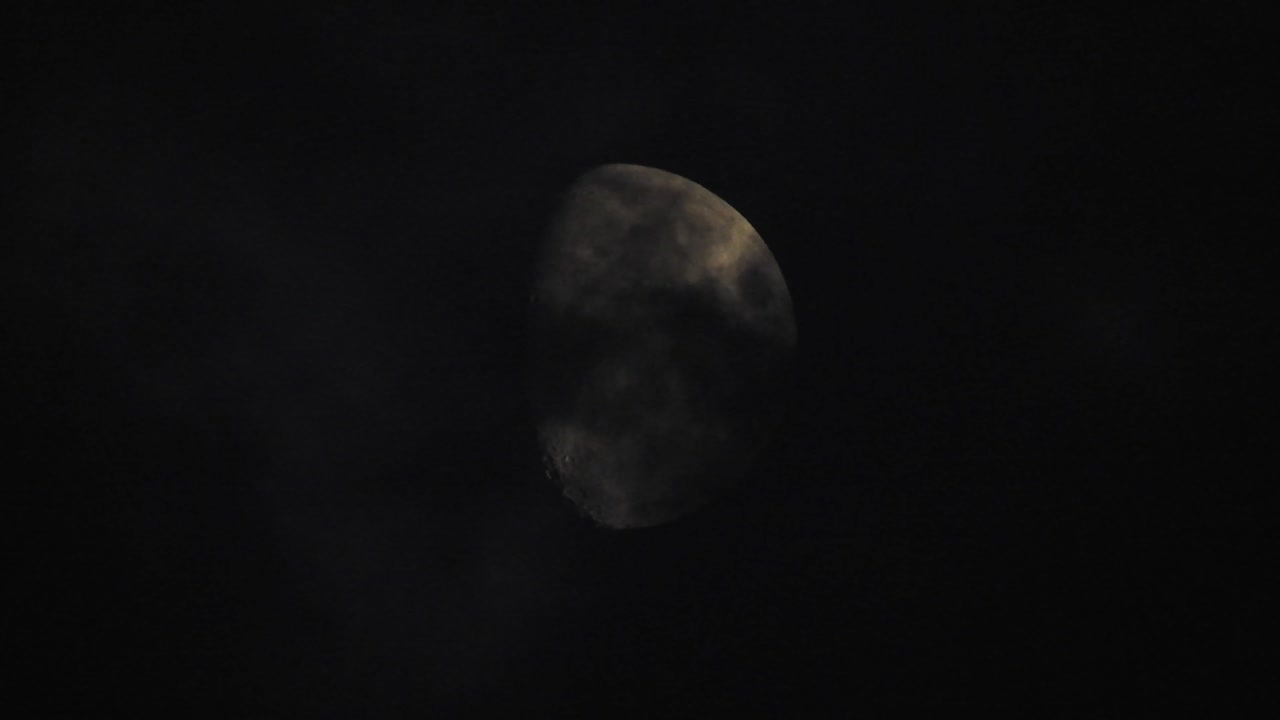 Moon at night with cloud real time. 4k video moon in the black sky.  Clouds passing by moon at night. night sky with cloudy weather