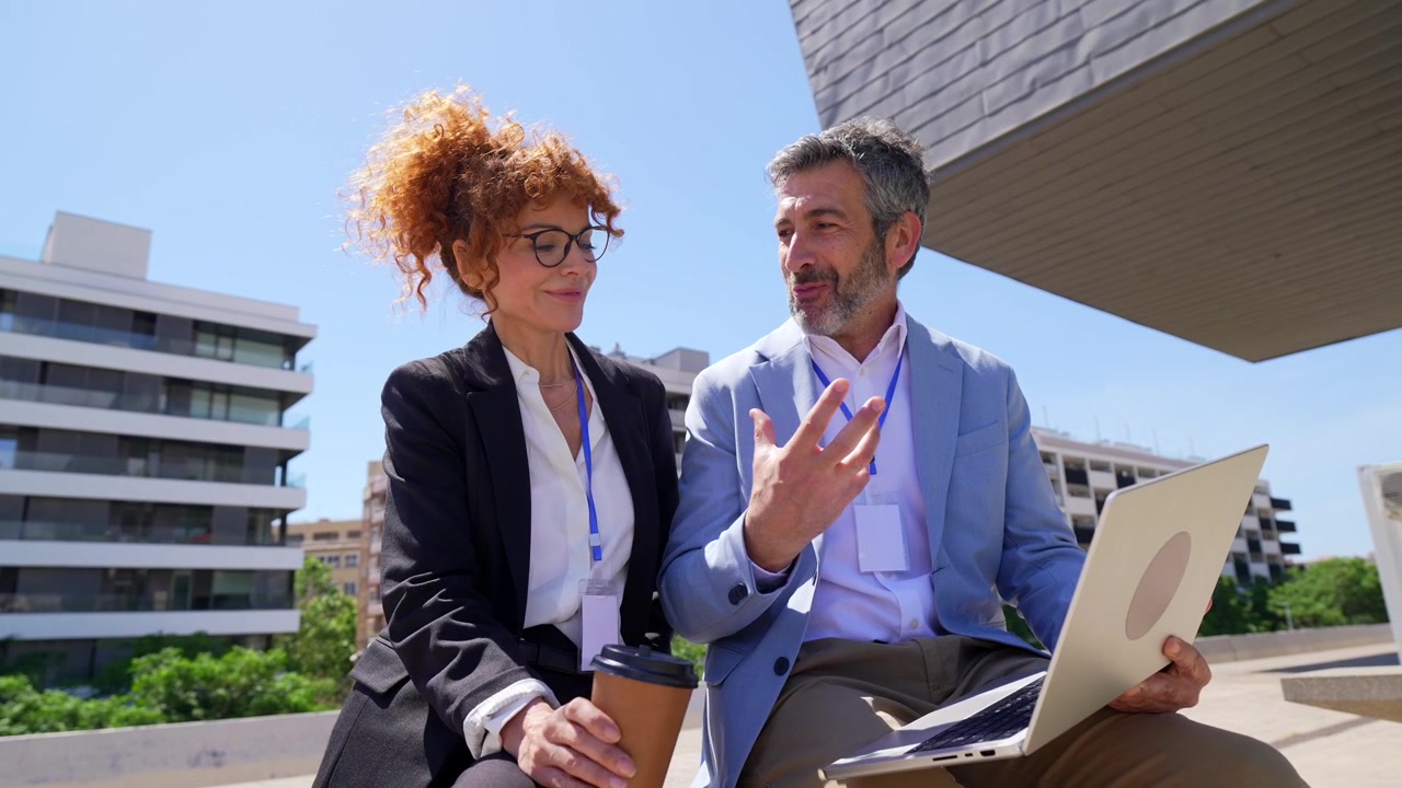 Professionisti aziendali che discutono un progetto al laptop all'aperto