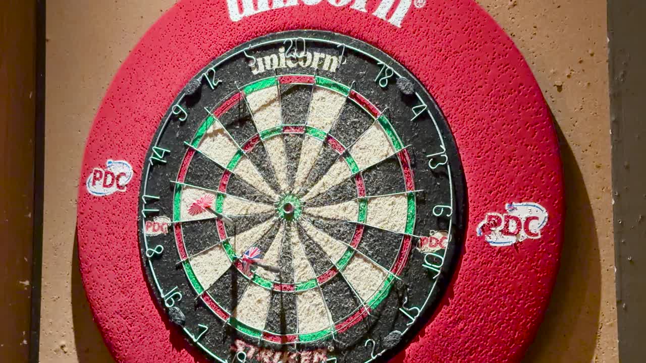 Darts striking dartboard in well-lit indoor Bangkok location, static camera, close-up perspective