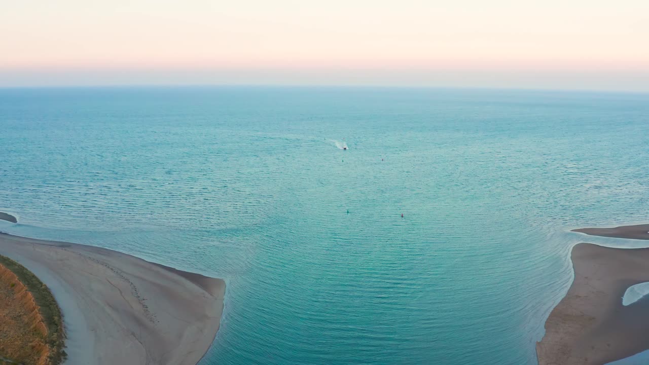 Aerial Drone Shot Flying Toward the Sea at Sunset with Boat Returning to Shore
