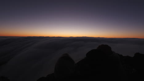 Excursionistas-Abrazándose-Y-Disfrutando-De-La-Puesta-De-Sol,-Por-Encima-De-Las-Nubes-En-La-Cumbre-De-Una-Montaña,-En-El-Parque-Nacional-Hassell,-Australia-Occidental