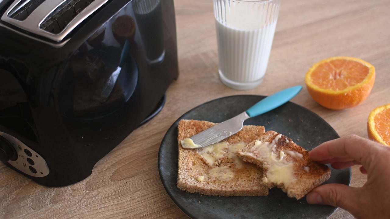 Hand picking up buttered toast from a breakfast plate