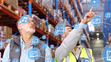 Animation-of-network-of-connections-with-icons-over-man-and-woman-working-in-warehouse