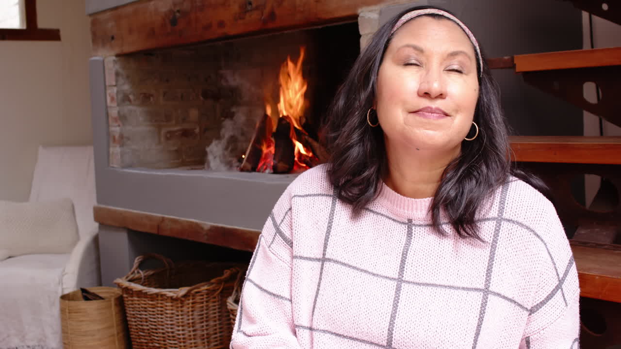 Cozy at home, senior woman relaxing by fireplace, enjoying peaceful moment