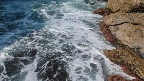 aerial view of waves crashing against a rocky shore