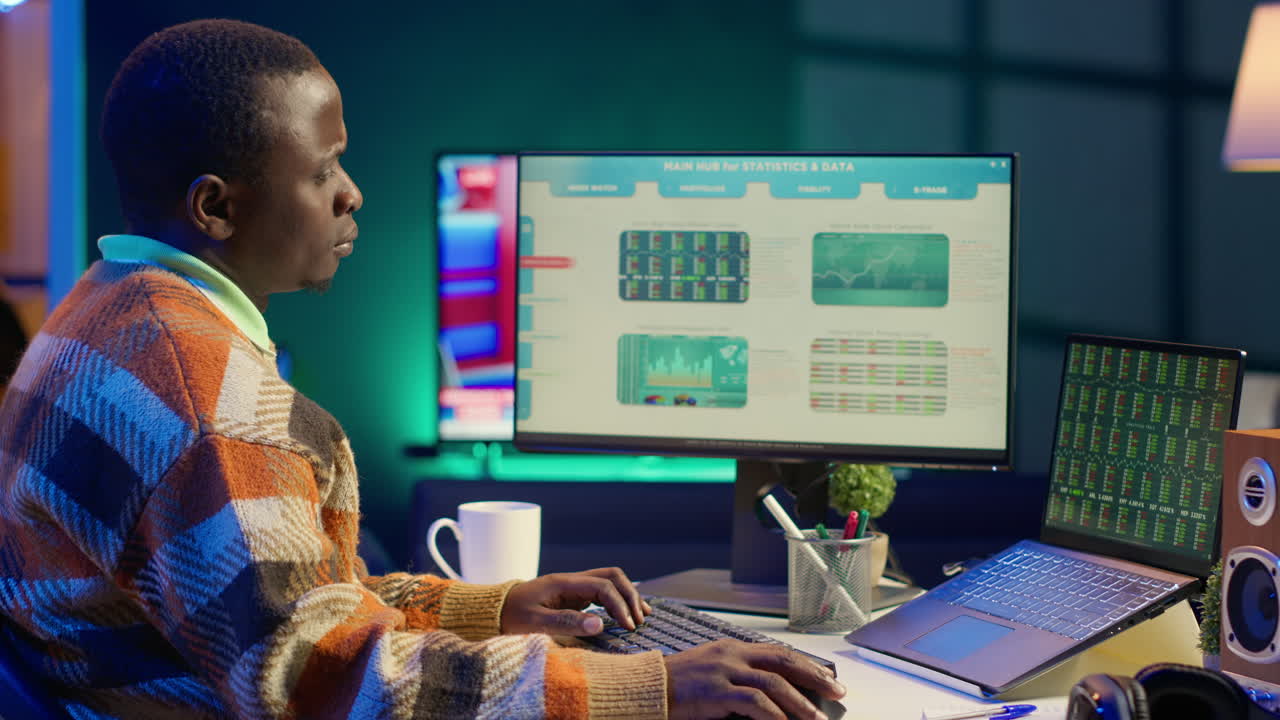 Man working on stock market analysis with computer and laptop