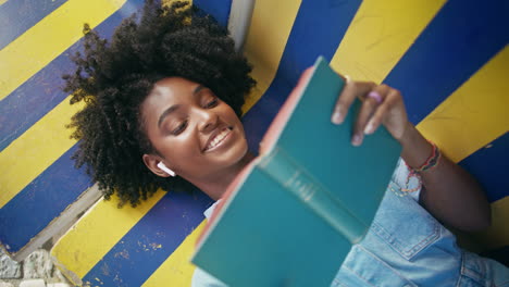 mujer joven relajándose al aire libre y leyendo un libro