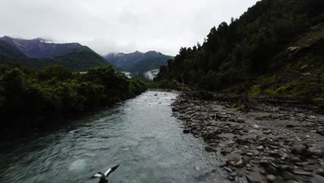 Slow-motion-FPV-shot-above-a-fast-flowing-stream-at-the-base-of-mountains-in-New-Zealand