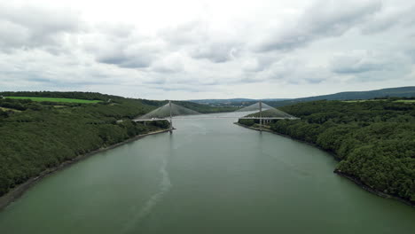 Vista-Aérea-Del-Dolly-Delantero-De-Un-Puente-Colgante-Sobre-El-Río.