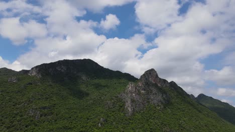 imágenes aéreas deslizándose hacia la derecha de esta hermosa montaña rocosa que revela estas nubes esponjosas que proyectan sombras en el parque nacional khao sam roi yot, prachuap khiri khan, tailandia