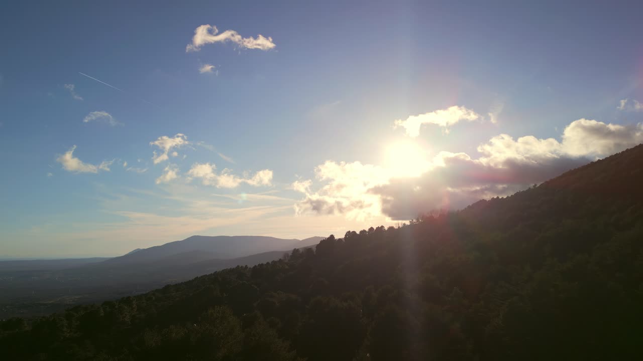 Sole splendente su paesaggio montano verde con cielo blu.