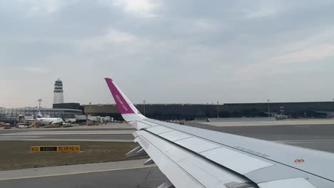 Wizz-Air-plane-wing-in-the-international-airport-of-Vienna,-Flughafen-Wien-Schwechat-during-the-day-4K