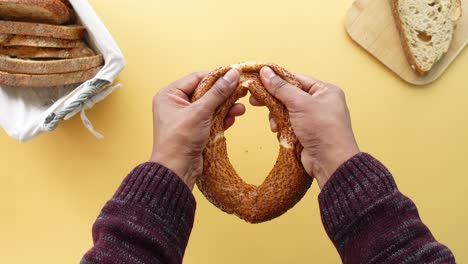 person breaks a sesame seed bread