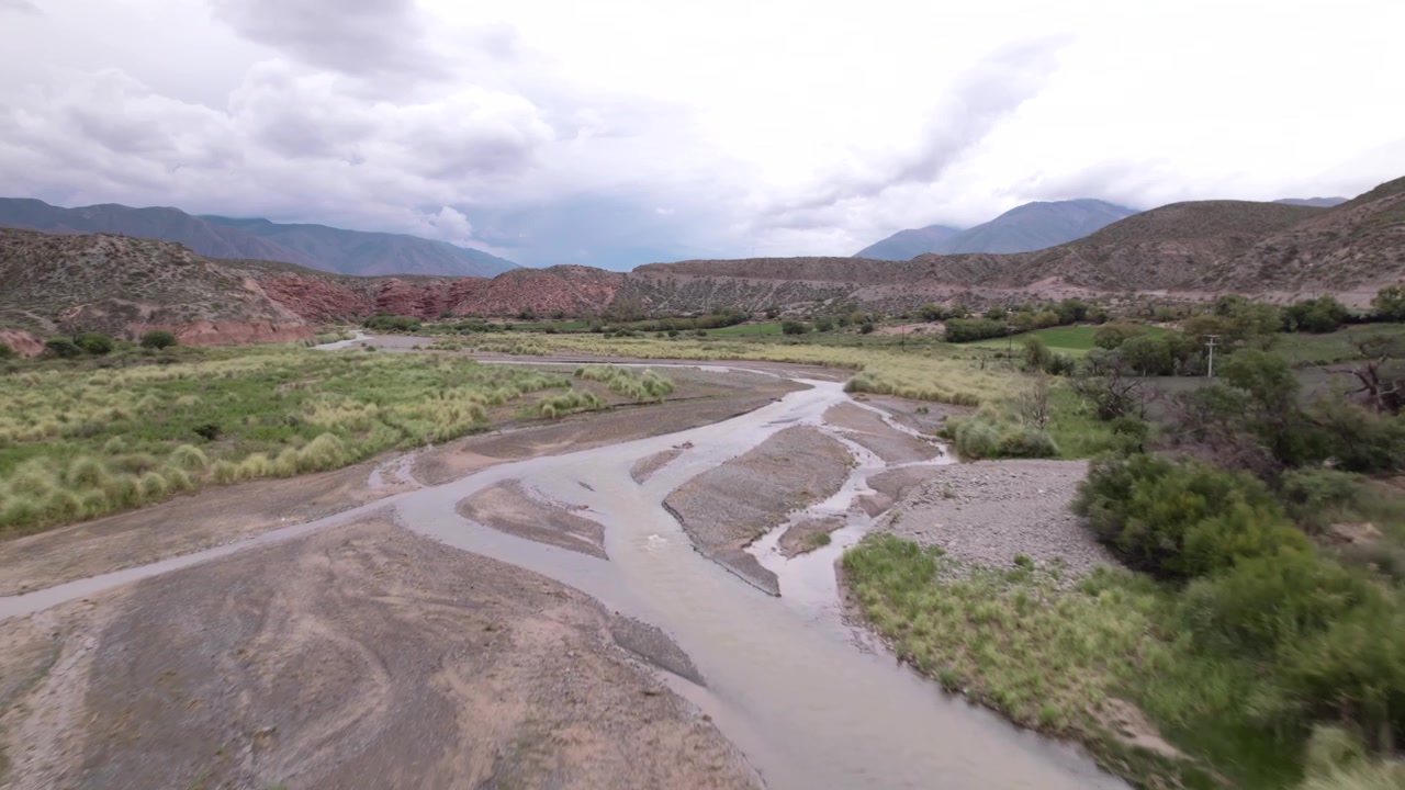 Vista aérea de drone 4K de La Poma, Salta, Argentina. Deslumbrante paisagem andina com montanhas de rocha vermelha, vales verdes e um rio atravessando o cenário dramático do cânion.