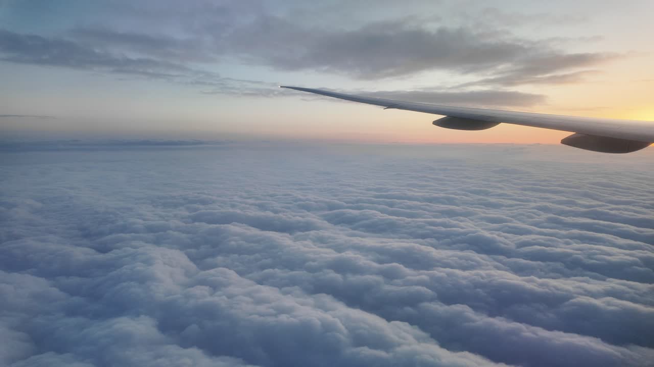 View from an airplane wing over clouds at sunrise or sunset