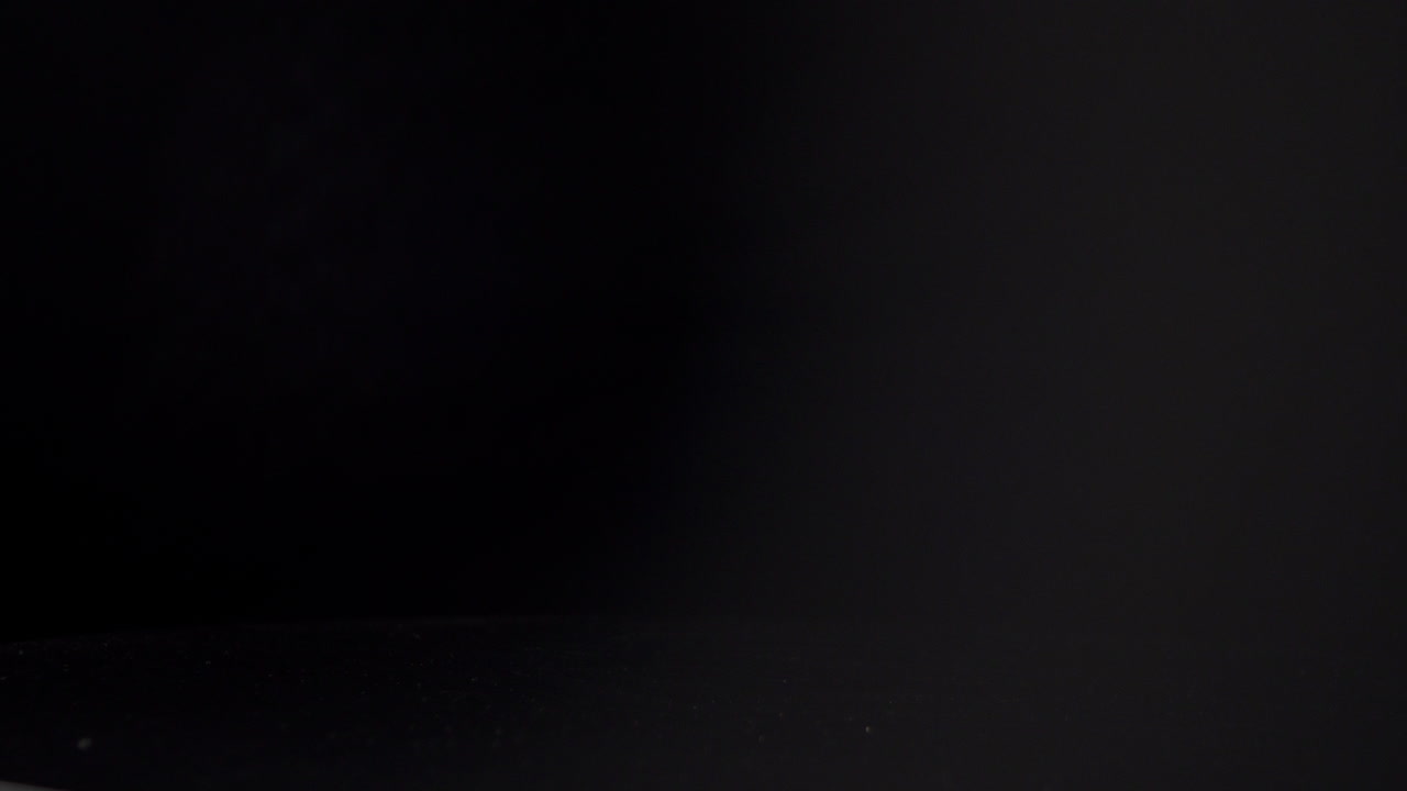 la mano de la persona gira la taza blanca en la mesa contra el fondo negro