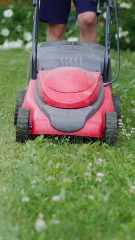 boy mowing the lawn. close-up. vertical video