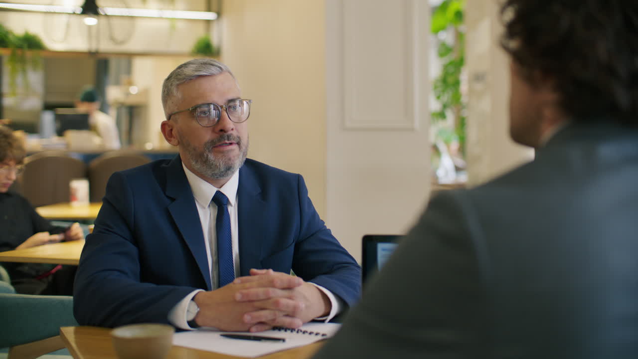 Cadre supérieur serrant la main d’un collègue après la signature d’un accord dans un café