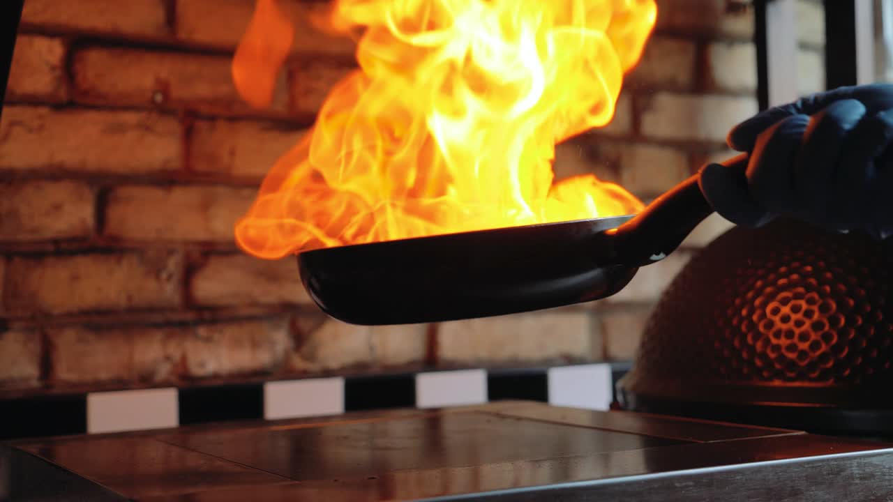 Chef sautes mushrooms with flames in restaurant while flipping around food.