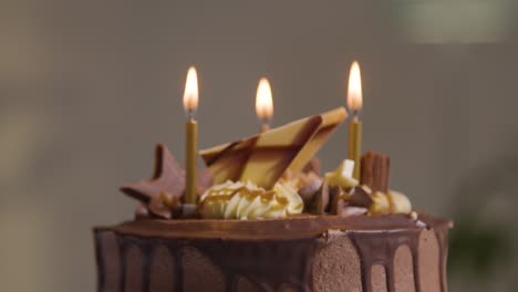 primer plano de pastel de celebración de cumpleaños de chocolate decorado con velas que se apagan en la fiesta en casa