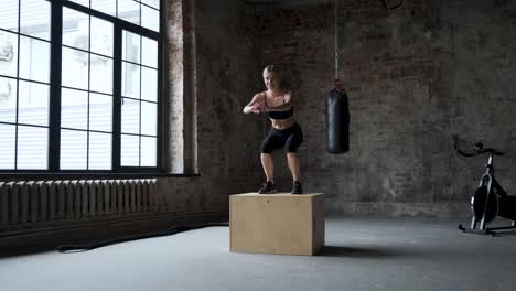 fit athletic woman does box jumps in the deserted factory gym