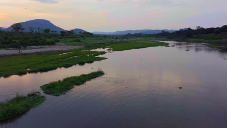 Drohneneingang-Krüger-Nationalpark-Luftbild-Filmischer-Orange-rosa-roter-Sonnenuntergang-Am-Fluss-Südtor-Vögel-Flamingo-Krokodil-Unten-Regnerisches-Frühlingsgrün-üppige-Atemberaubende-Berglandschaft-Vorwärtsbewegung