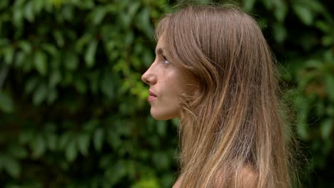 Perfil-De-Una-Mujer-Joven-Atractiva-Con-Una-Expresión-Seria-En-Su-Rostro-Contra-Un-Fondo-Floral-Verde