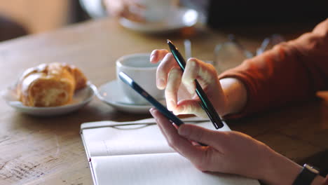 Coffee-shop,-smartphone-and-hands-with-notebook