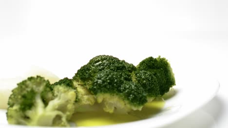 gustosi broccoli con piatto di olio d'oliva su sfondo bianco, dolly in tiro