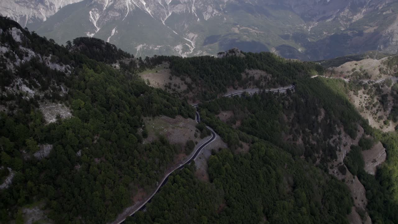 video con un dron panorámico descriptivo frontal que avanza en el sh21 bajando al valle theth, mostrando toda la zona montañosa del norte de albania, con el monte korab al fondo