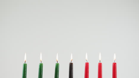 varias velas coloridas y dos calabazas contra un fondo gris
