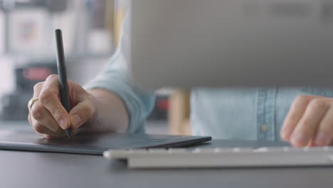 close up of hands of male architect in office working on desktop computer using graphics tablet