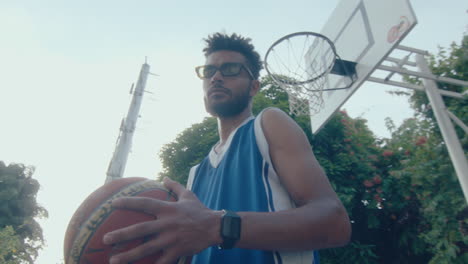 young handsome man posing with basketball on outdoor court