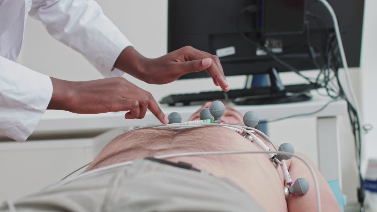 Kardiyoloji test ekipmanı olan bir doktor için hastanın uzuvlarındaki elektrotları takan hastane hemşiresi