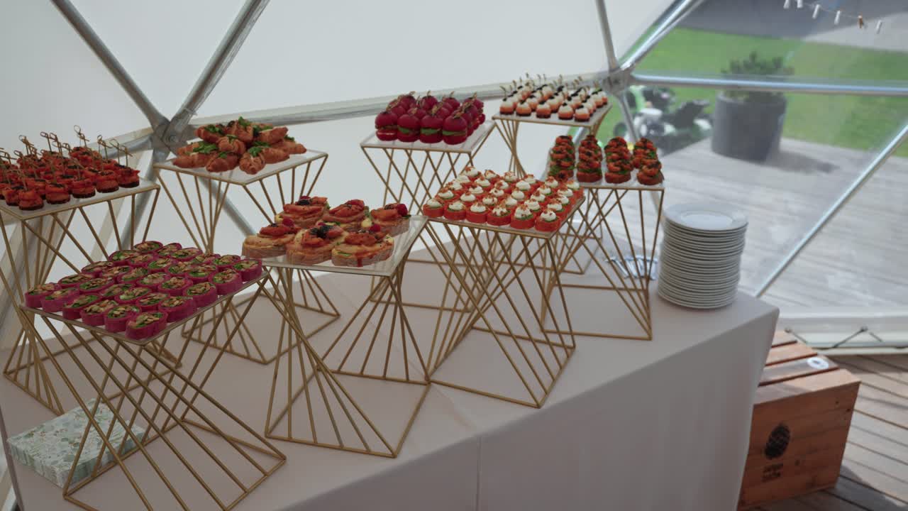 Elegant catering table with colorful gourmet appetizers arranged on modern geometric stands, perfect for weddings, events, and upscale celebrations