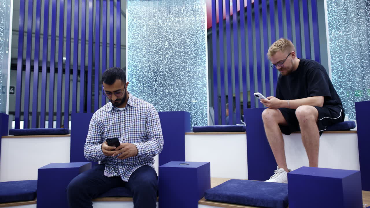 dos hombres usando teléfonos inteligentes en un espacio de exposición moderno