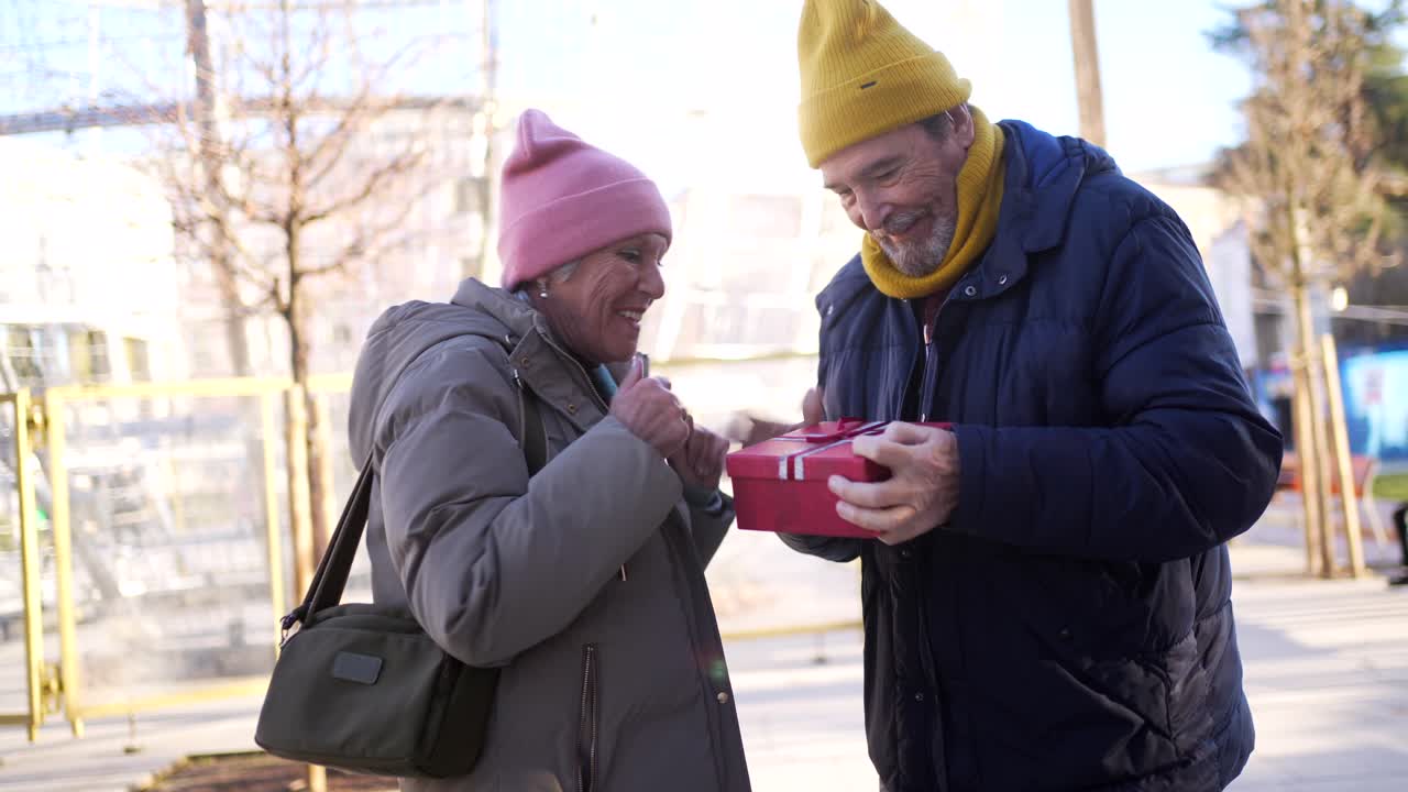 Senior Couple Exchanging a Gift Outdoors