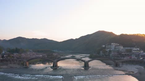 Revelación-De-Inclinación-Aérea-De-4k-Del-Puente-Iwakuni-Kintaikyo-Al-Amanecer,-Primavera-En-Japón