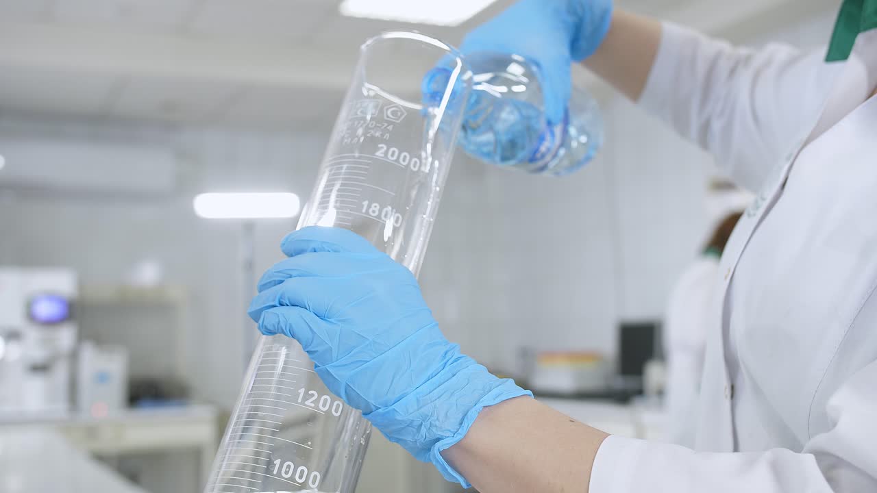 Scienziato che versa acqua in un cilindro graduato