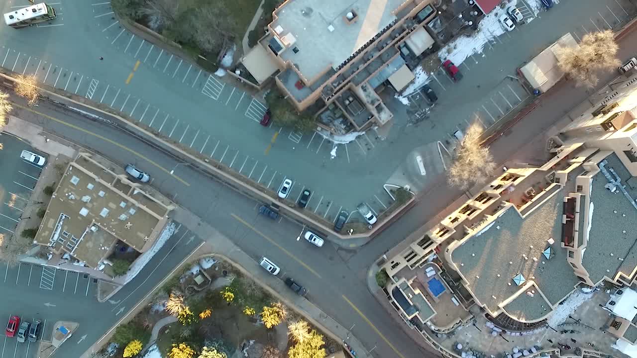 Aerial shot of birds fluttering over curving roads near Santa Fe Plaza in Old Town, New Mexico. Light snow patches, historic buildings, and dynamic city movement from a bird’s eye view